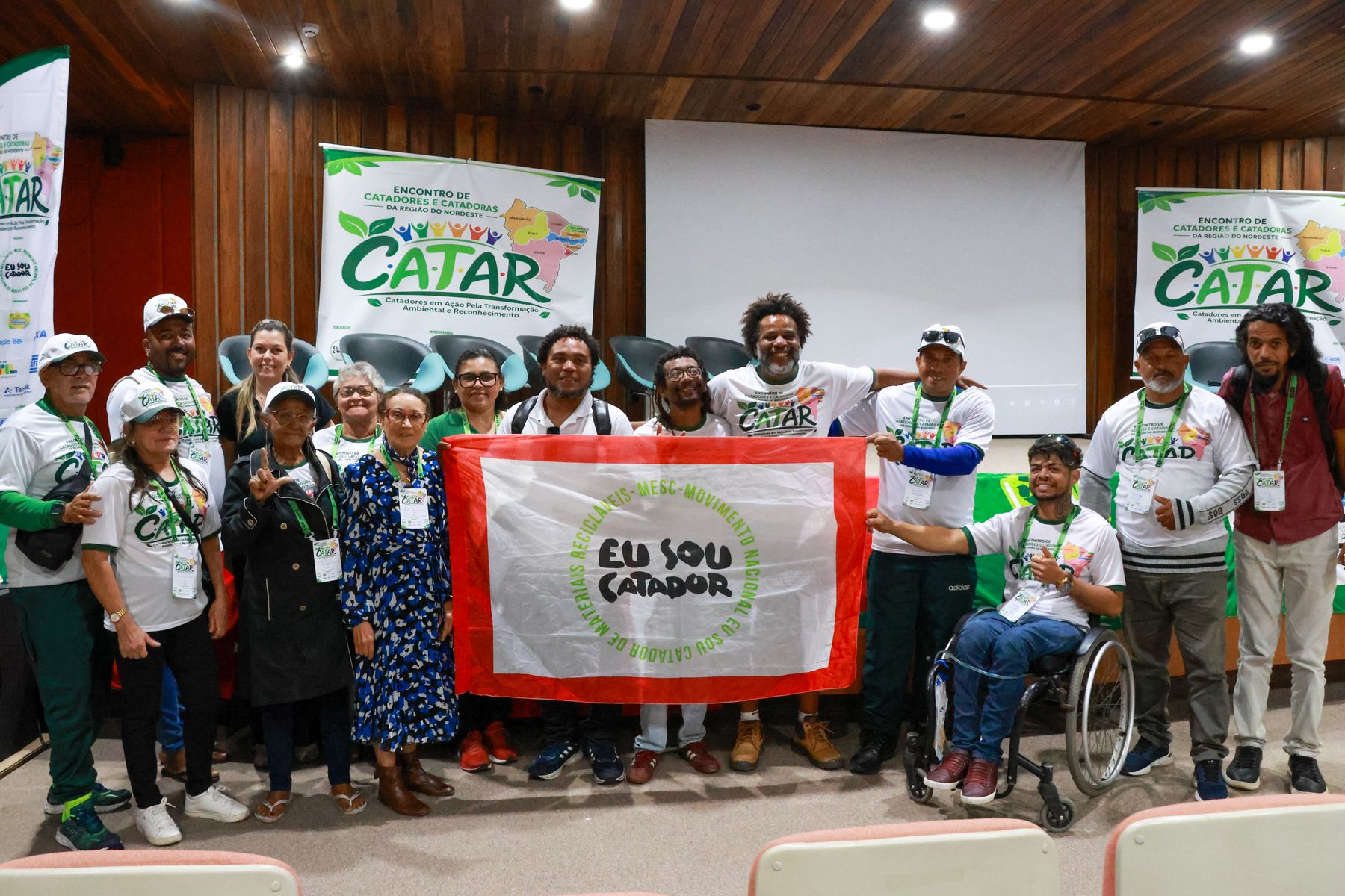 Grupo de catadoras e catadores com a bandeira Eu Sou Catador no palco