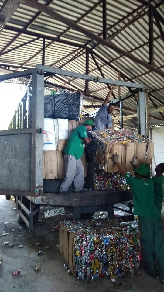 Catadores carregam fardos de latas em um caminhão