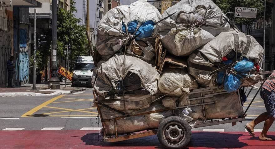 Carroça de catador carregada de sacos atravessa rua no centro de São Paulo
