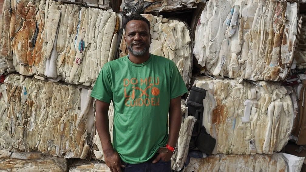 Catador diante de fardos de material reciclável