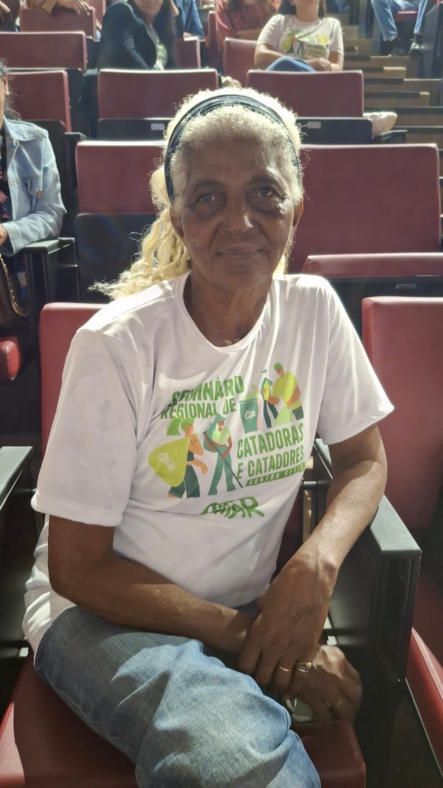 Catadora sentada em auditório durante encontro CATAR