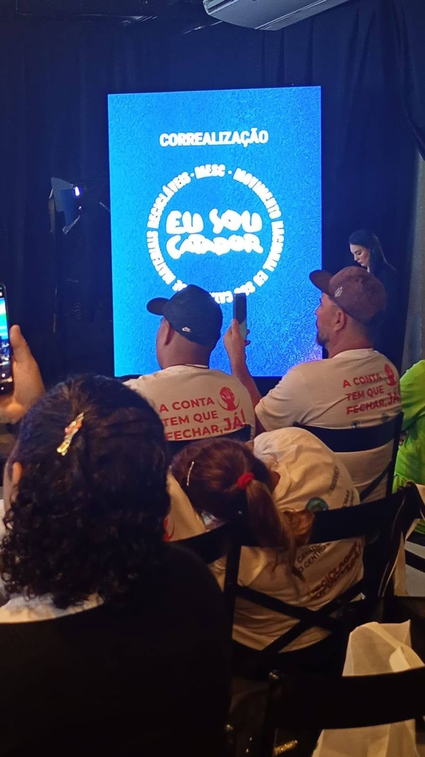 Telão com o logotipo do MESC em evento com catadores
