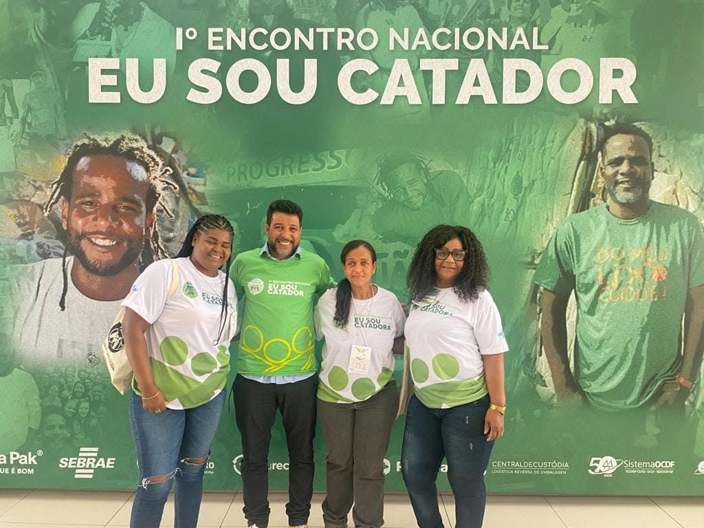Catadoras e apoiador diante do painel do 1º Encontro Nacional Eu Sou Catador