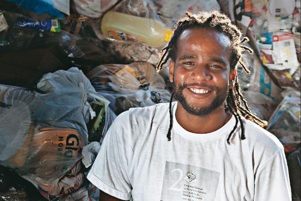 Tião Santos sorrindo diante de sacos de materiais recicláveis